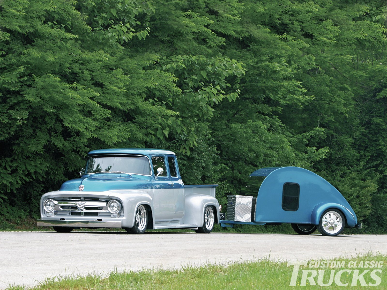 HD PC desktop wallpaper featuring a classic Ford F-100 truck towing a matching vintage teardrop camper against a lush green forest backdrop.