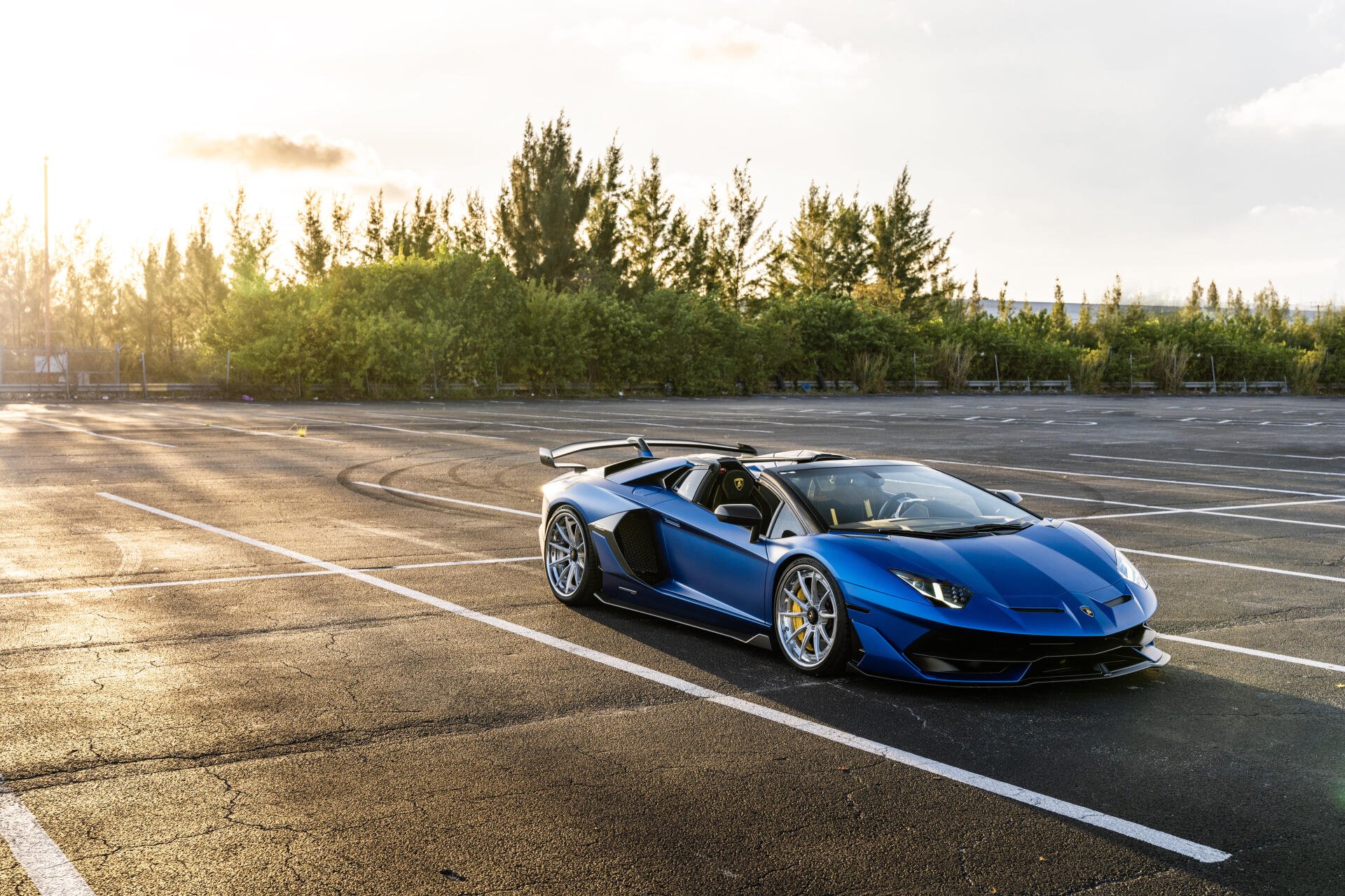 Blue Lamborghini sports car parked on an empty lot at sunset, captured in stunning 8K Ultra HD for a vivid PC desktop wallpaper background.