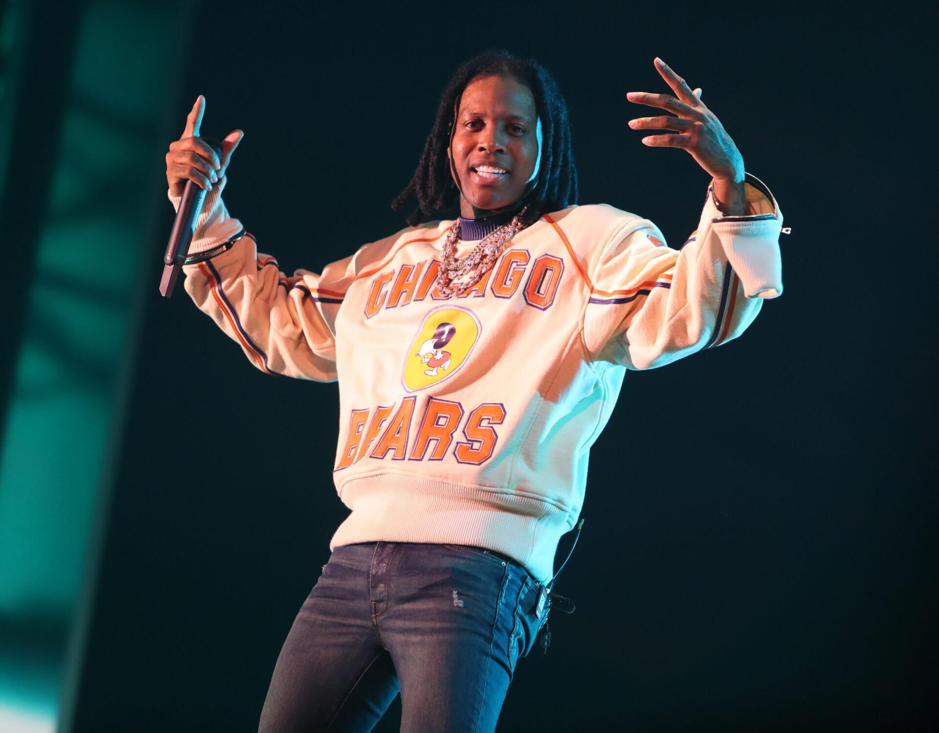A vibrant HD desktop wallpaper featuring rapper Lil Durk performing on stage, dressed in a Chicago Bears sweatshirt, exuding energy and confidence.