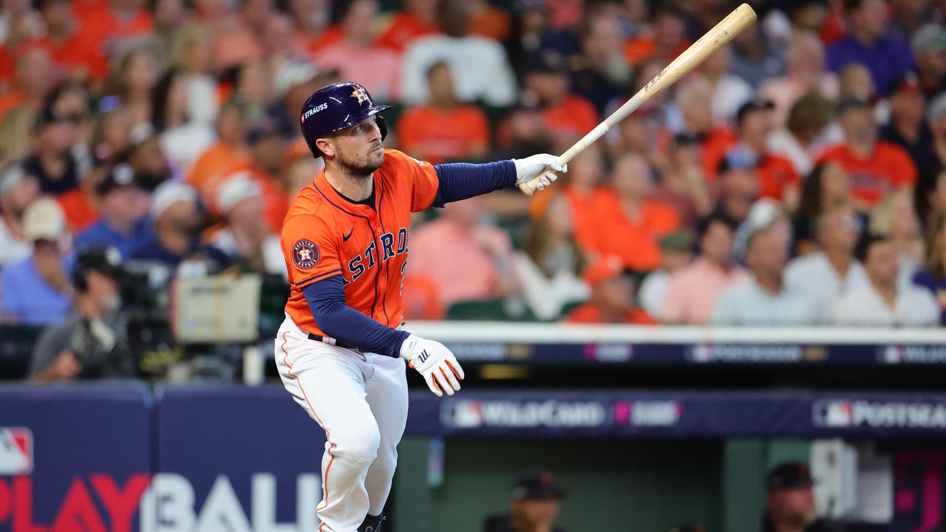 Alex Bregman of the Houston Astros swings his bat during an MLB game, surrounded by cheering fans in vibrant orange attire. HD desktop wallpaper capturing the excitement of baseball.