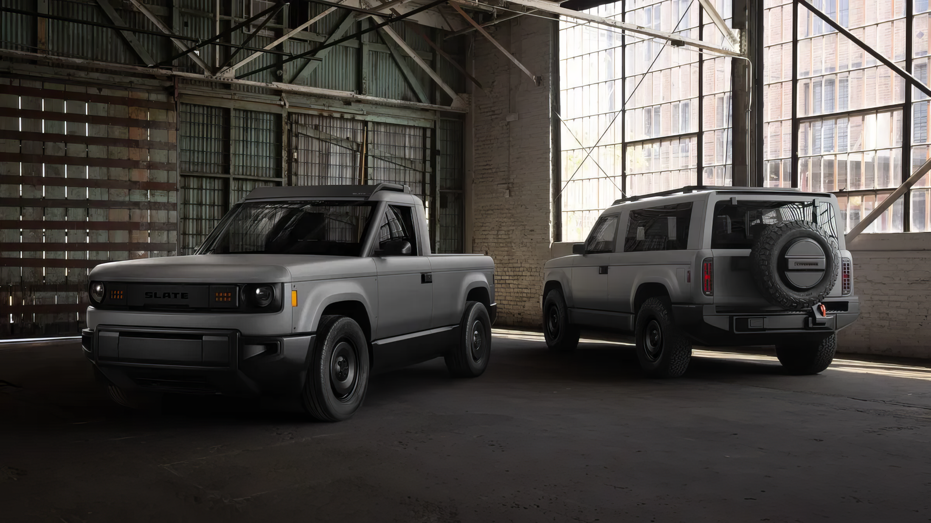 A slate-colored SUV and pickup truck from Slate Auto are parked side by side in an industrial setting, showcasing their rugged designs in this HD desktop wallpaper.