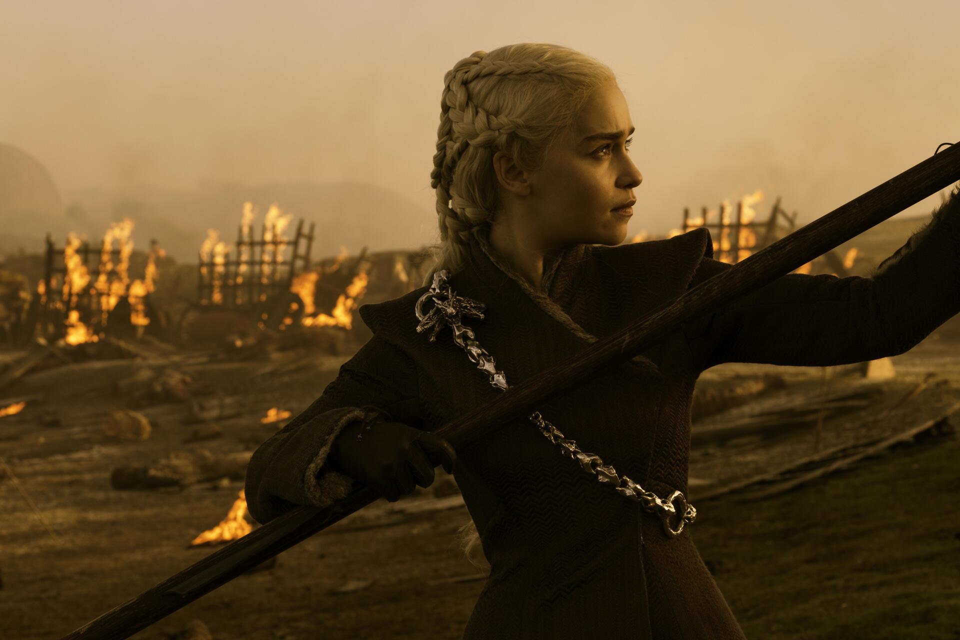 Game of Thrones 4K Ultra HD wallpaper featuring Daenerys Targaryen in battle-ready pose with a spear, fiery battlefield in the background.