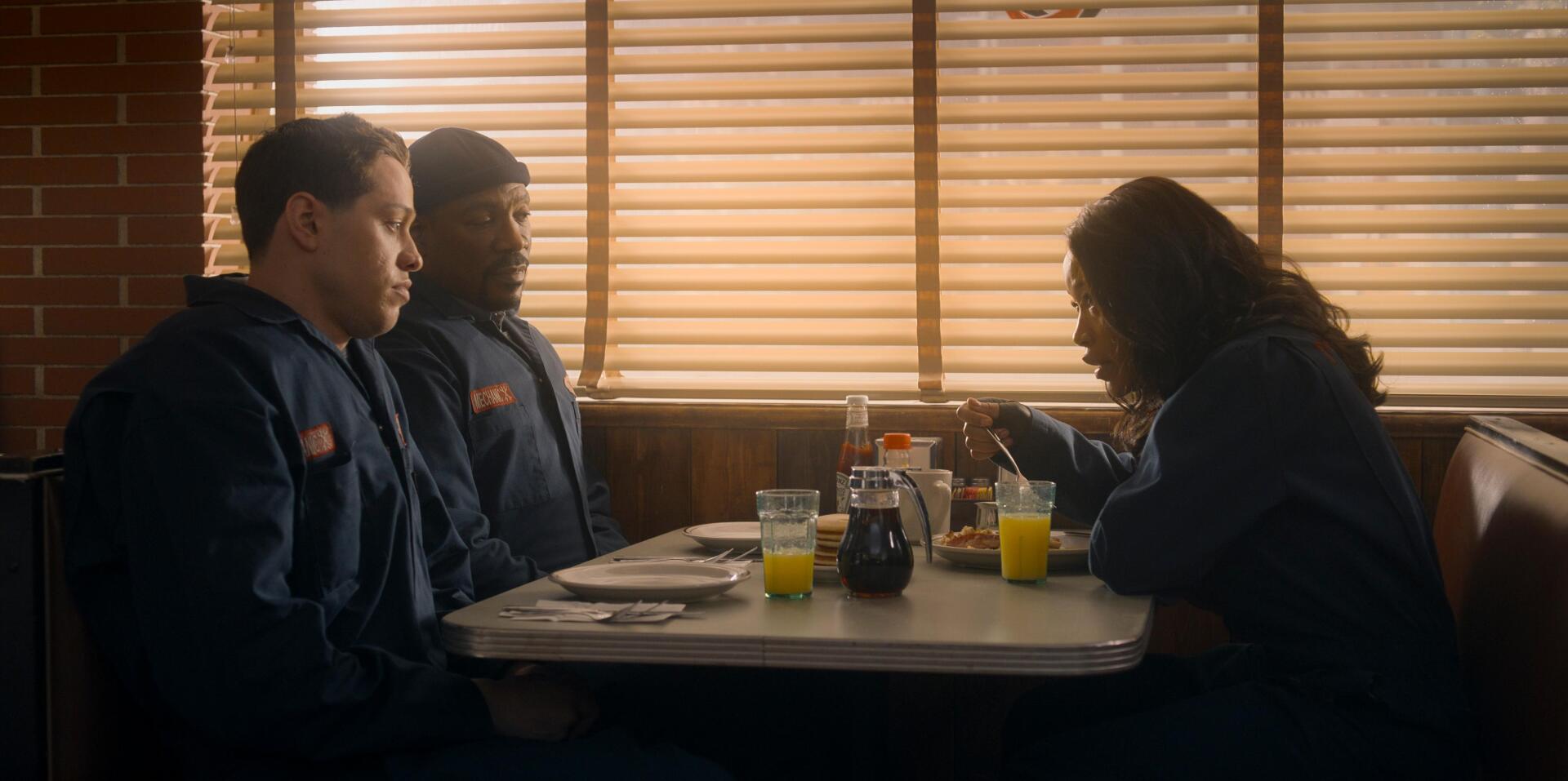 HD PC desktop wallpaper from the movie The Pickup, showing three people sitting at a diner booth with blinds casting warm light inside.