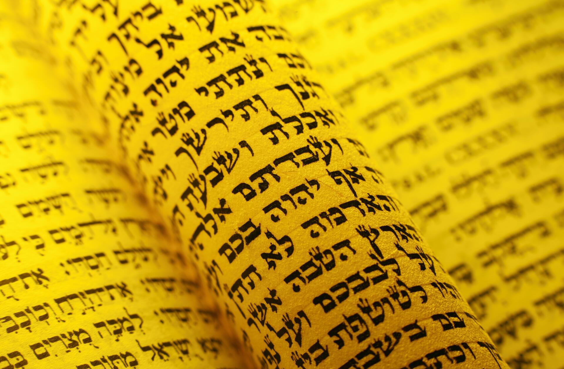 HD desktop wallpaper: close-up of a yellow Torah scroll covered in Hebrew script, representing Jewish religious text.