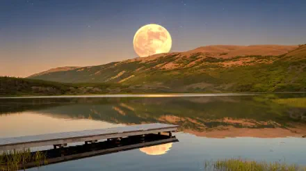 A stunning harvest moon rises over tranquil waters, casting reflections on the lake, with mountains in the background, creating a serene nature scene. 4K Ultra HD wallpaper.