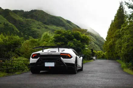 Rear view of a white Lamborghini Huracan sports car on a wet mountain road, surrounded by lush green hills — 5K Ultra HD PC desktop wallpaper/background.