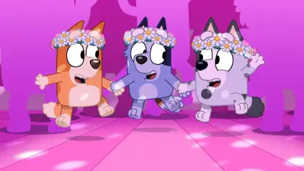 Three animated dogs from the TV show Bluey, adorned with floral crowns, joyfully dance together on a vibrant pink background. A lively scene for a HD PC desktop wallpaper.