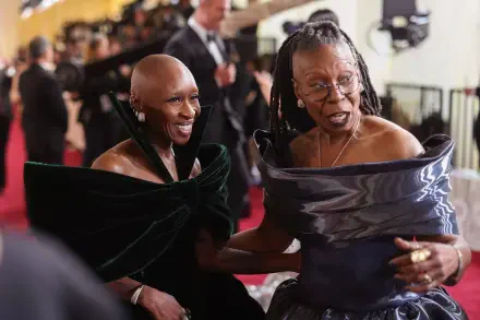 Whoopi Goldberg and Cynthia Erivo share a joyful moment at the Academy Awards, displaying elegance in stunning outfits against a glamorous event backdrop.