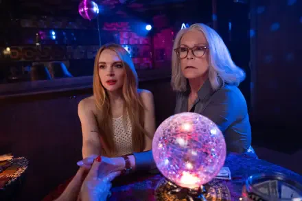 A vibrant scene from Freaky Friday, featuring Jamie Lee Curtis and Lindsay Lohan, captures their characters in a dimly lit, colorful setting with a crystal ball.