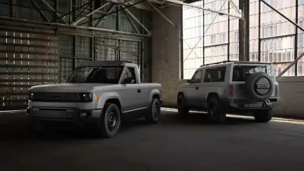 A slate-colored SUV and pickup truck from Slate Auto are parked side by side in an industrial setting, showcasing their rugged designs in this HD desktop wallpaper.