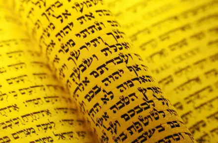 HD desktop wallpaper: close-up of a yellow Torah scroll covered in Hebrew script, representing Jewish religious text.
