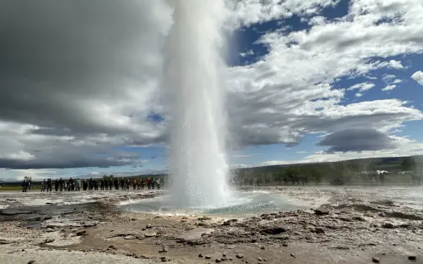 A stunning view of Strokkur Geyser in Iceland, capturing the powerful eruption surrounded by dramatic clouds, perfect for use as an HD desktop wallpaper or background.