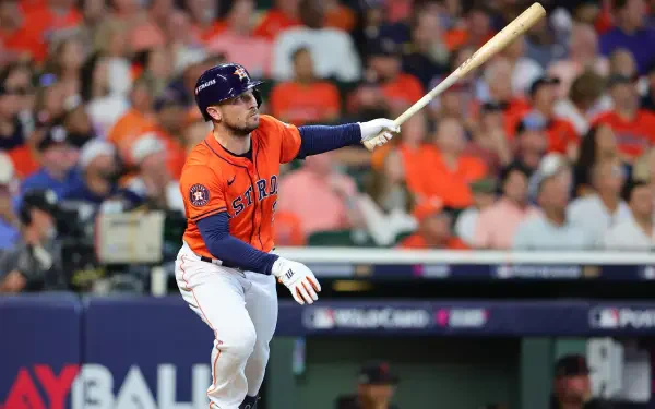 Alex Bregman of the Houston Astros swings his bat during an MLB game, surrounded by cheering fans in vibrant orange attire. HD desktop wallpaper capturing the excitement of baseball.