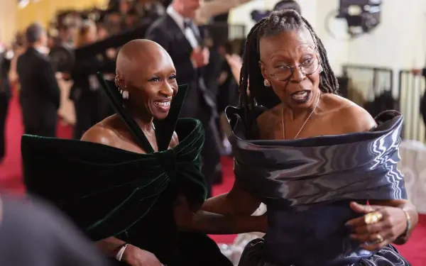 Whoopi Goldberg and Cynthia Erivo share a joyful moment at the Academy Awards, displaying elegance in stunning outfits against a glamorous event backdrop.