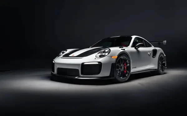A sleek silver Porsche 911 GT2 RS Weissach is showcased against a dark backdrop, highlighting its aggressive design and performance features in stunning 8K Ultra HD quality.