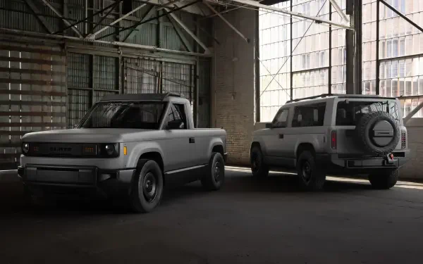 A slate-colored SUV and pickup truck from Slate Auto are parked side by side in an industrial setting, showcasing their rugged designs in this HD desktop wallpaper.