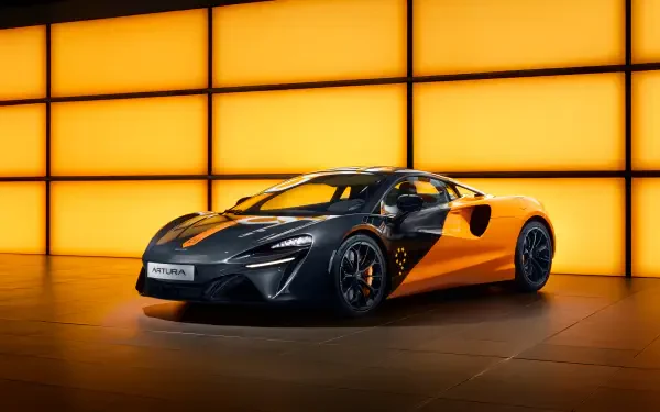 A sleek yellow and black McLaren Artura sports car showcased against a glowing orange grid backdrop. 4K Ultra HD PC desktop wallpaper and background.