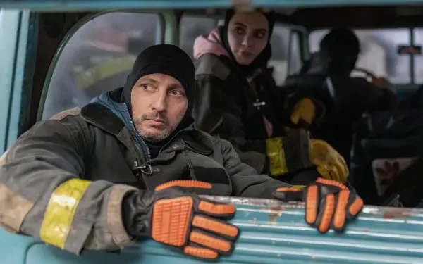 Scene from the TV show The Eternaut featuring characters in firefighter gear inside a vehicle, used as an HD PC desktop wallpaper and background.