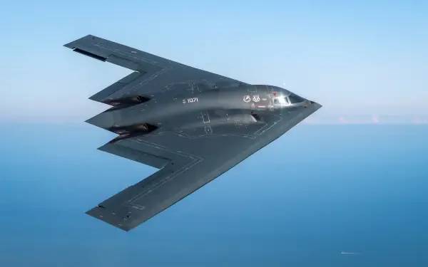 HD desktop wallpaper of a Northrop Grumman B-2 Spirit military bomber aircraft in flight over the ocean, representing advanced air force technology.