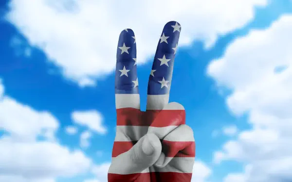 HD PC desktop wallpaper: a hand painted with the American flag making a victory/peace V sign against a bright blue sky, celebrating the 4th of July.