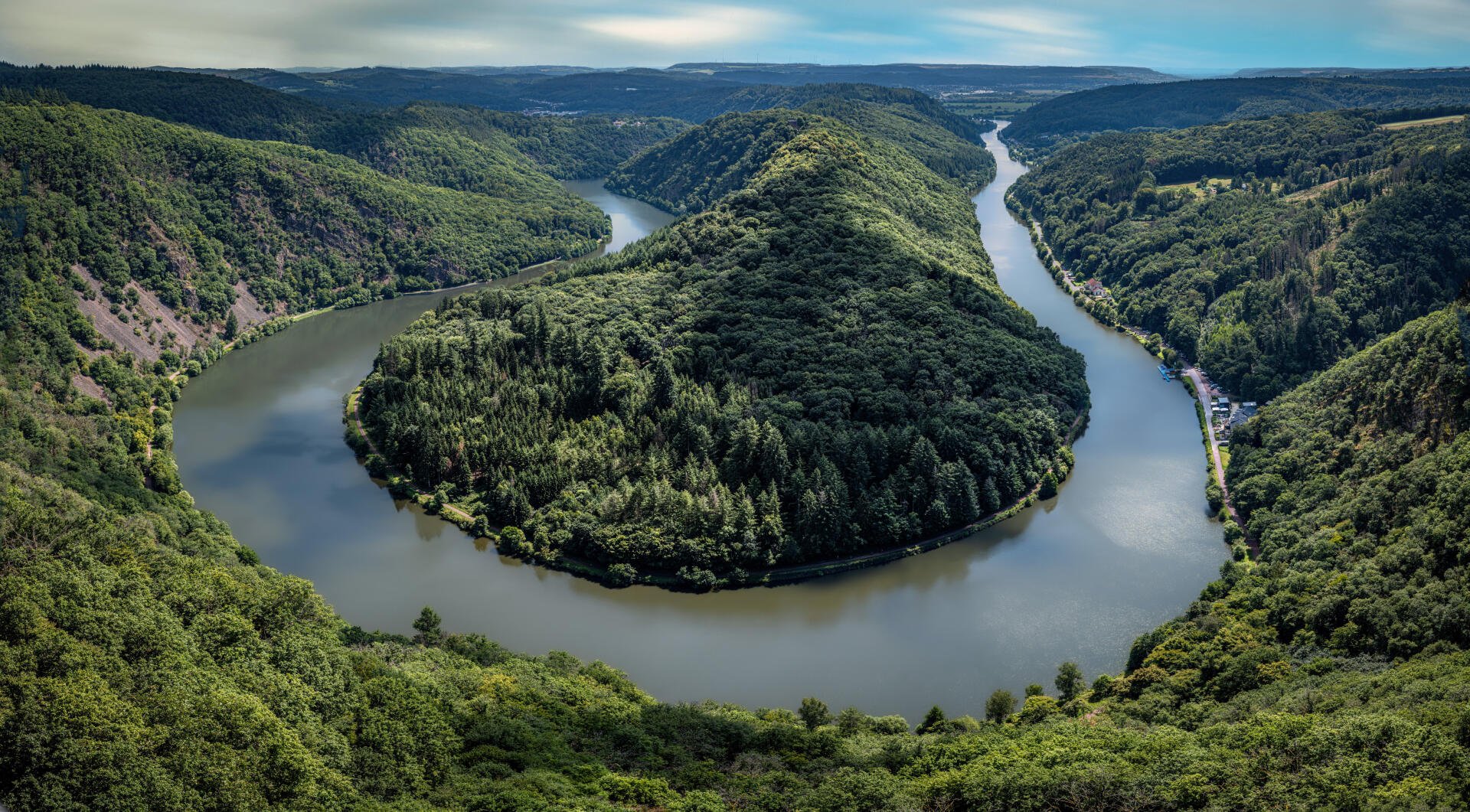 Aerial nature photograph of a winding river carving through dense forest; 4K Ultra HD nature photography rendered as a PC desktop wallpaper and background.