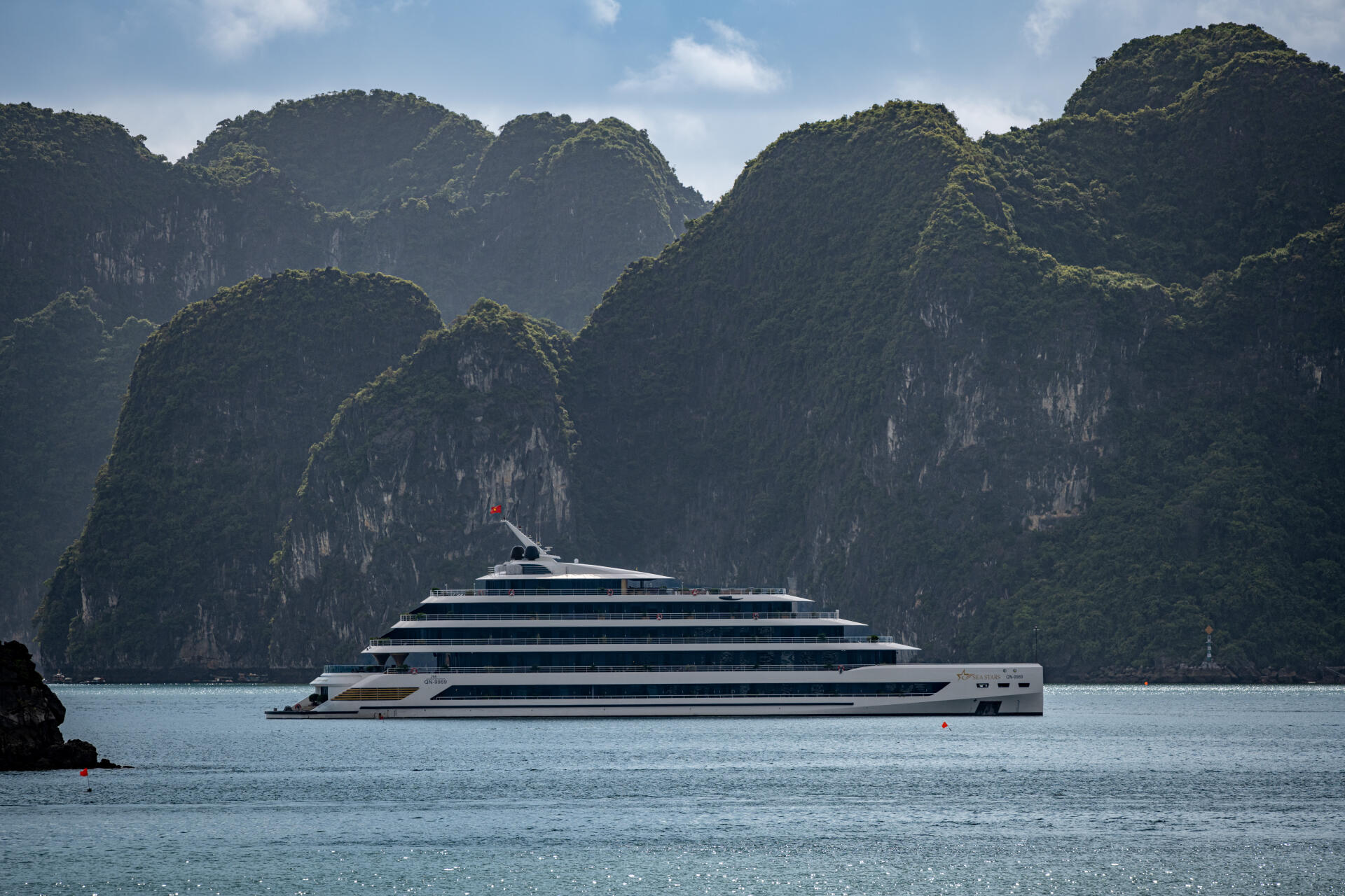 5K Ultra HD desktop wallpaper: luxury cruise ship on calm ocean with towering green limestone mountains in Vietnam under soft daylight.