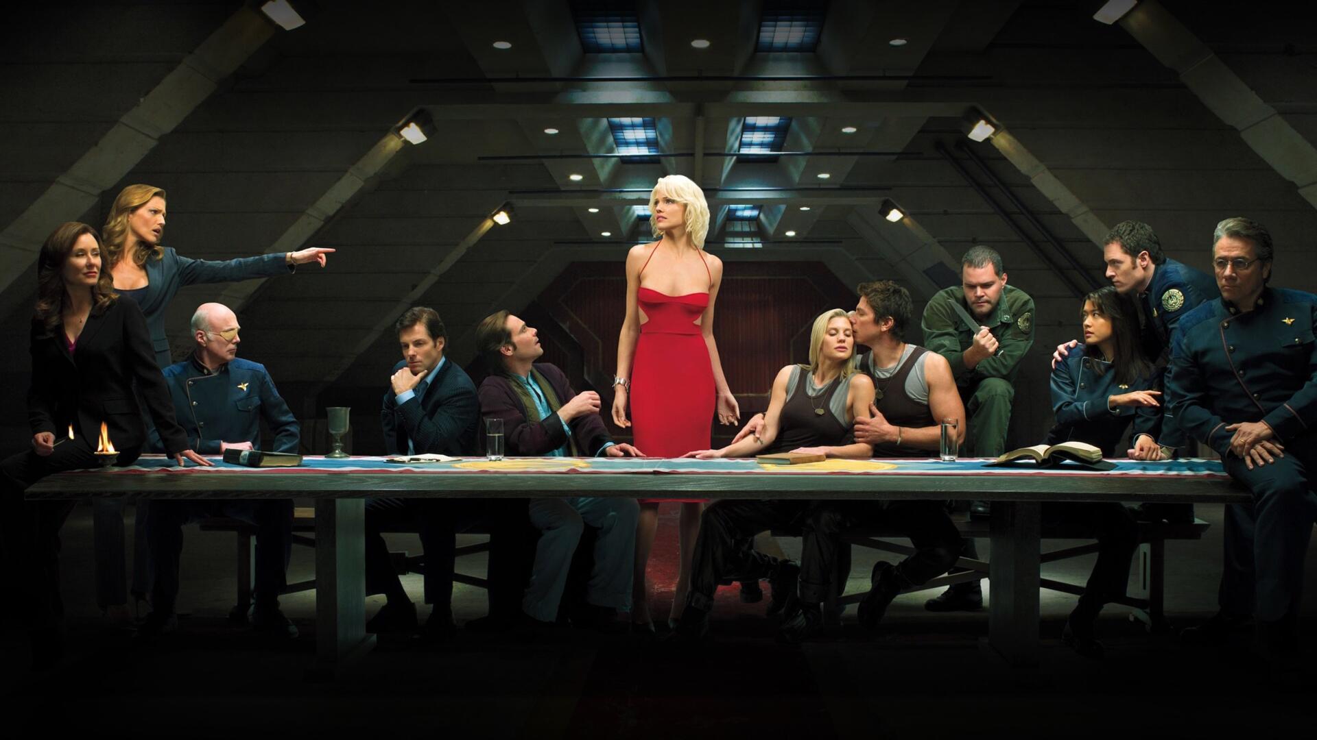 Battlestar Galactica (2003) scene: dim war-room with crew around a long table; a woman in a red dress stands center. 2K Quad HD PC desktop wallpaper and background.