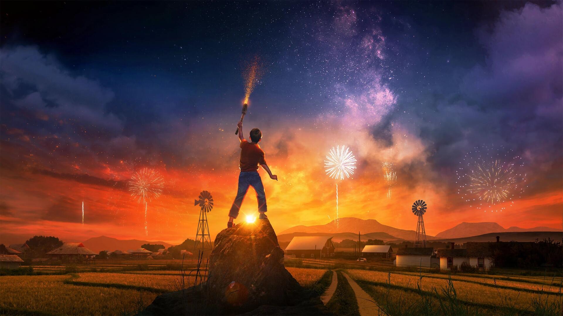 Artistic sunset landscape 2K Quad HD PC desktop wallpaper: a boy stands on a rock with a sparkler, fireworks and stars above farmland and windmills.