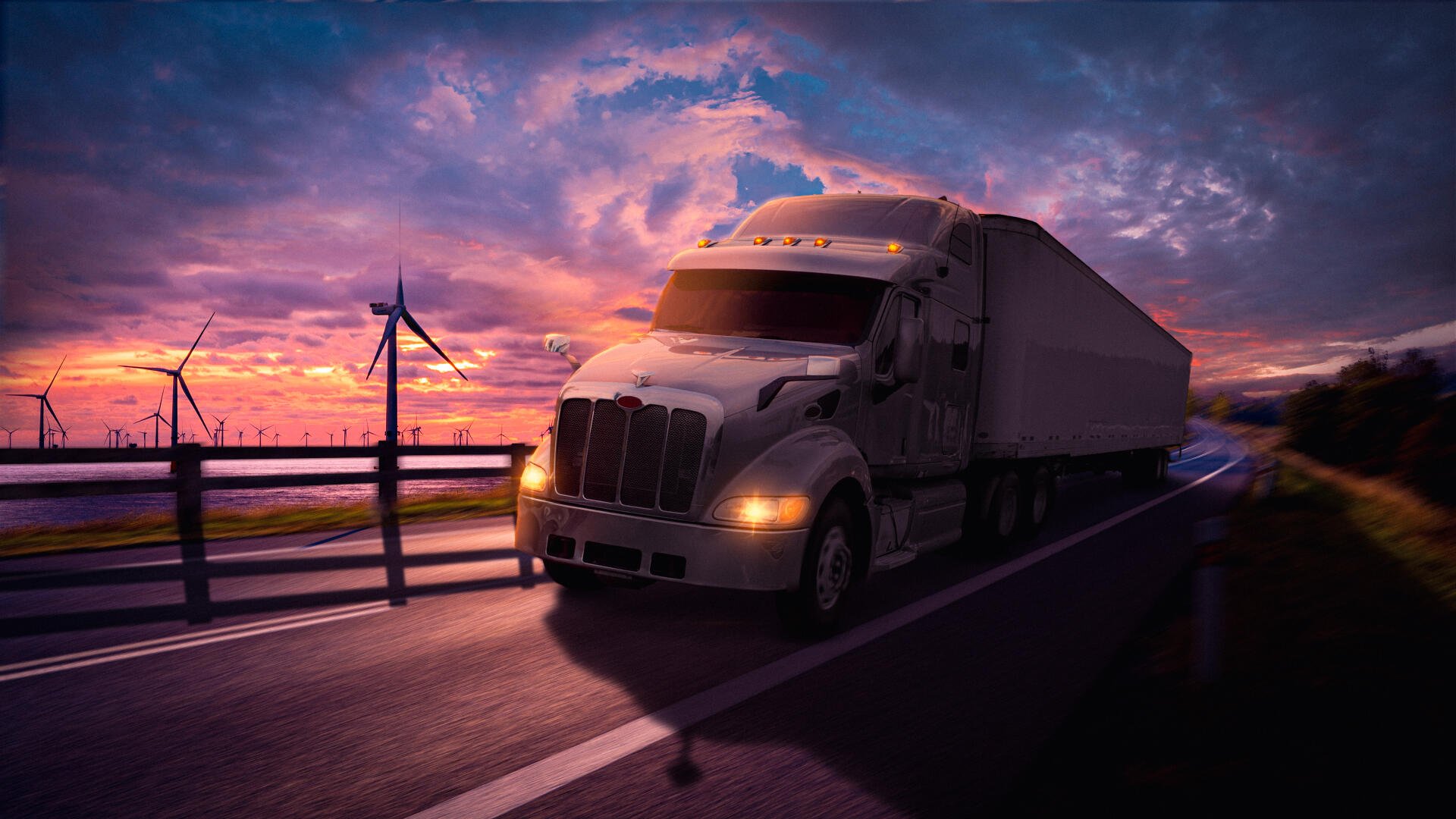 Truck hauling a trailer along a wet highway at sunset, wind turbines on the horizon and dramatic clouds — 4K Ultra HD PC desktop wallpaper and background.
