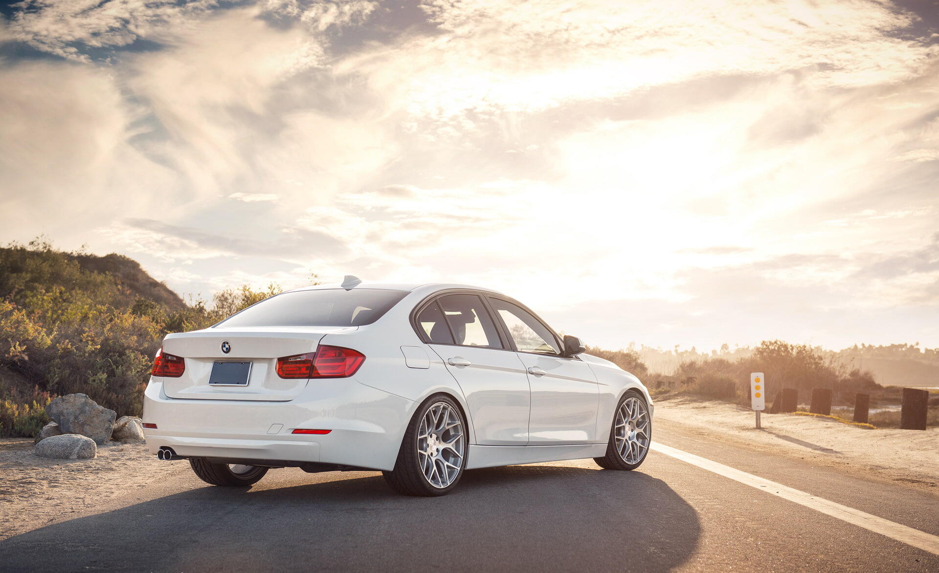 White BMW 328i parked on a sunlit coastal road, HD PC desktop wallpaper and background.