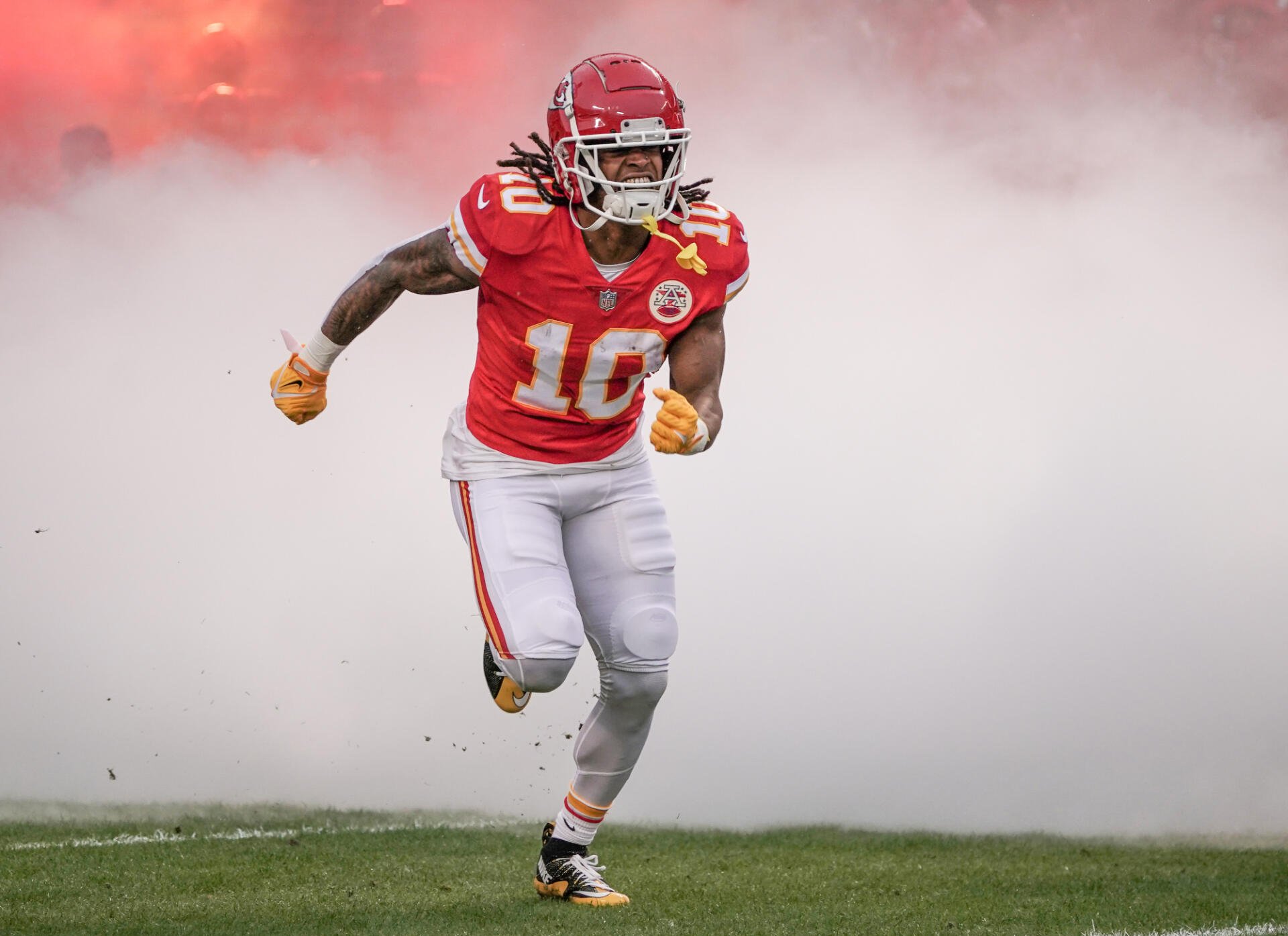 HD desktop wallpaper of a Kansas City Chiefs football player sprinting onto the field through stadium smoke in full red uniform.