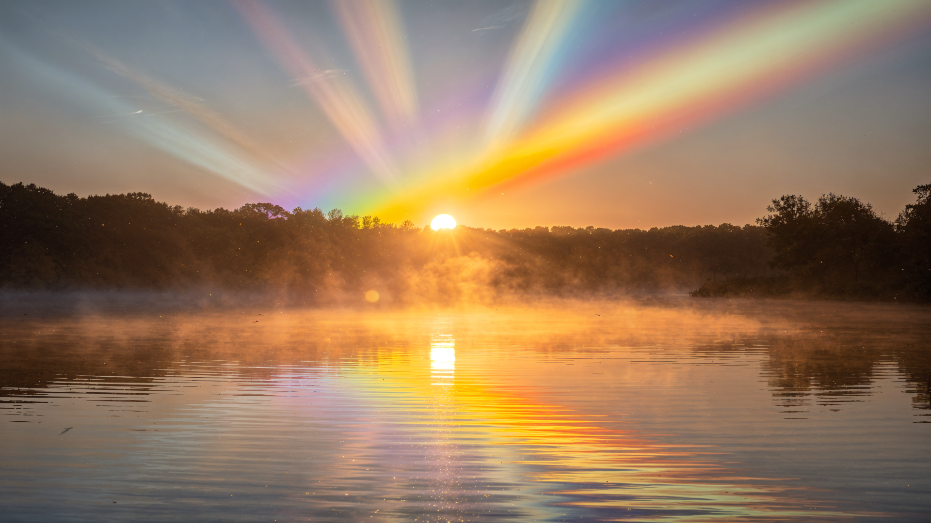 4K Ultra HD PC desktop wallpaper and background: sunrise over a misty lake, golden sun and rainbow-like rays fanning across the sky, reflected in calm water with a silhouetted treeline.
