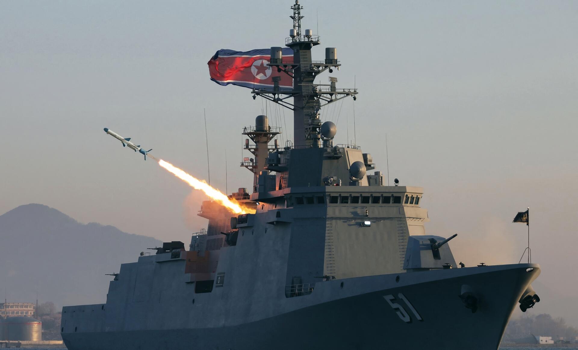 4K Ultra HD PC desktop background of a Choe Hyon-class guided missile destroyer launching a missile at sea; military naval fleet warship framed by distant mountains.