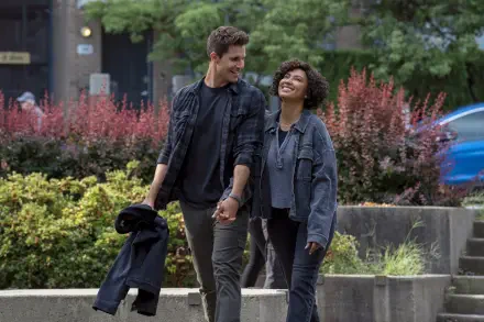 HD PC desktop wallpaper from the TV show Upload: two actors — a man and a woman — walk hand in hand through a city park, smiling and chatting.