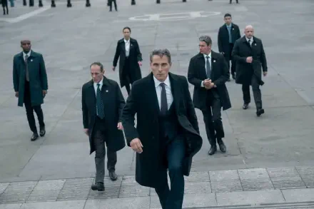 2K Quad HD PC desktop wallpaper of a suited lead from the TV show The Diplomat striding up stone steps, flanked by men in suits and security detail.
