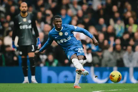 HD desktop wallpaper: Chelsea F.C. midfielder in blue kit firing a shot during a soccer match, crowd and an opponent blurred in the background.