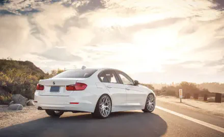 White BMW 328i parked on a sunlit coastal road, HD PC desktop wallpaper and background.