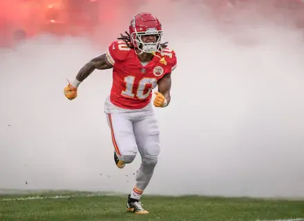 HD desktop wallpaper of a Kansas City Chiefs football player sprinting onto the field through stadium smoke in full red uniform.