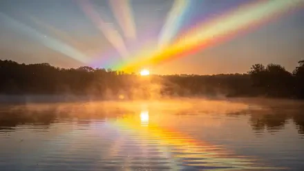 4K Ultra HD PC desktop wallpaper and background: sunrise over a misty lake, golden sun and rainbow-like rays fanning across the sky, reflected in calm water with a silhouetted treeline.