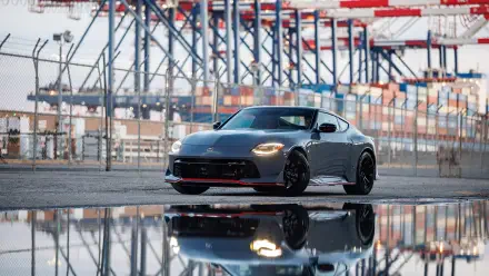Gray Nissan Z Nismo sports car at an industrial port, reflected in wet pavement — 4K Ultra HD PC desktop wallpaper and background.