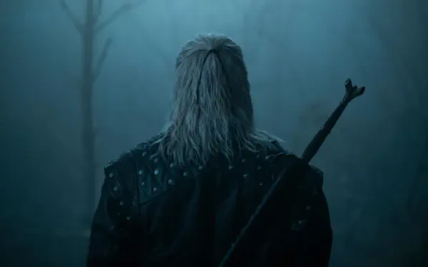 Rear view of Geralt of Rivia from The Witcher TV show, sword on his back in a misty blue forest — 8K Ultra HD PC desktop wallpaper/background.