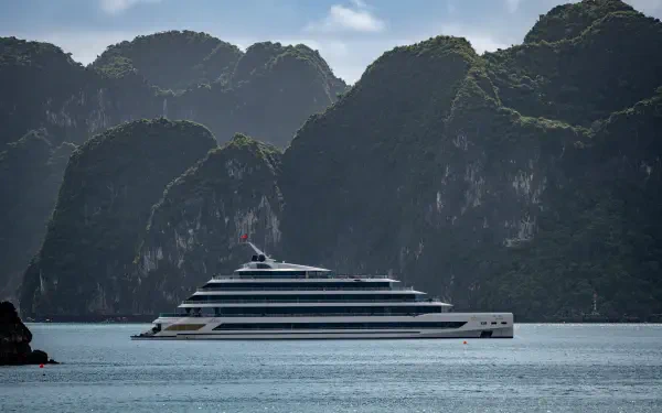 5K Ultra HD desktop wallpaper: luxury cruise ship on calm ocean with towering green limestone mountains in Vietnam under soft daylight.