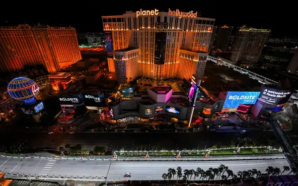 Night aerial shot of Las Vegas, USA — illuminated Planet Hollywood and surrounding casino buildings at night; 2K Quad HD PC desktop wallpaper/background.