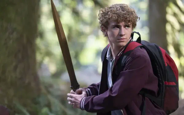 HD PC desktop wallpaper of Percy Jackson and the Olympians (TV show): a young hero grips a sword with a backpack, poised in a sun-dappled forest.
