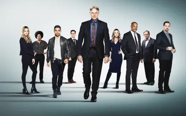 NCIS 4K Ultra HD PC desktop wallpaper: nine-person ensemble in suits and casual gear walking toward camera on a pale backdrop with cinematic, high-contrast lighting.