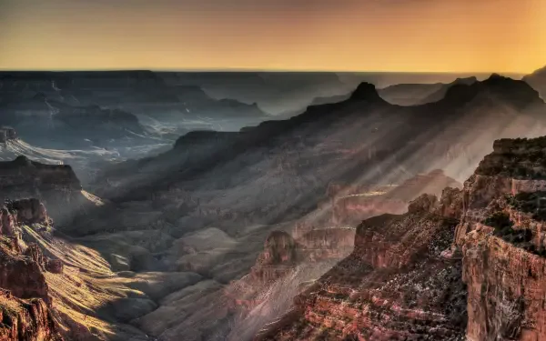 5K Ultra HD desktop wallpaper of the Grand Canyon in Arizona, USA — sun rays streaming over layered canyon ridges at sunrise.
