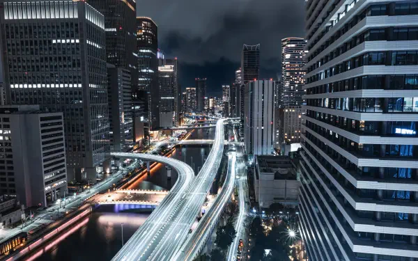 4K Ultra HD PC desktop wallpaper of Osaka, Japan — a nightscape of illuminated highways threading between high-rise buildings, with streaking light trails and glowing city lights.