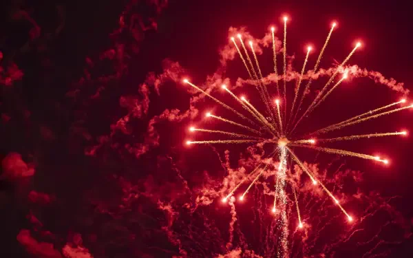 Red fireworks burst across a smoky night sky in a celebratory display — 4K Ultra HD PC desktop wallpaper and background.