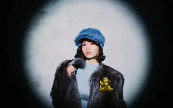 4K Ultra HD PC desktop wallpaper of a model in a blue fur hat and dark fur coat, posed under a soft circular spotlight on a gray backdrop.