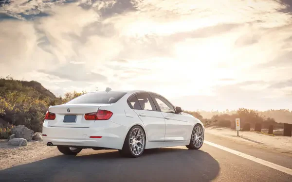 White BMW 328i parked on a sunlit coastal road, HD PC desktop wallpaper and background.